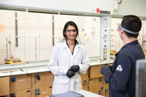 Graduate researcher talks to colleague in lab
