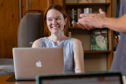 student smiling while sitting in front of laptop