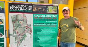 Dylan Driscoll poses next to a poster for the Cloughjordan Ecovillage.