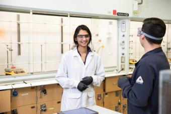 Graduate researcher talks to colleague in lab