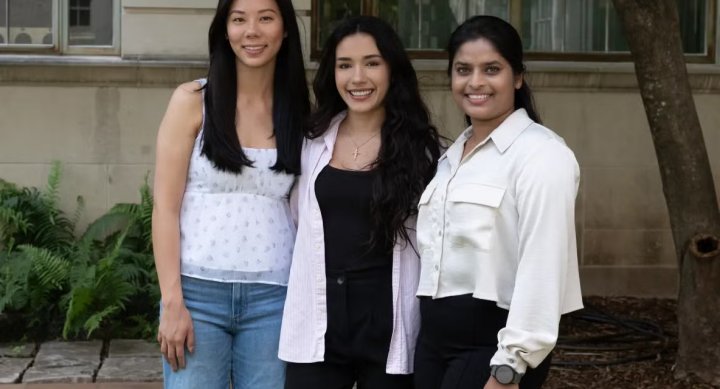Winnie Lin, Ashley Sparks, and Nandita Warrier stand in front of a UT campus building in business casual clothes.