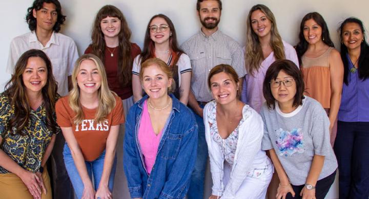 Twelve education students take a group photo against a white wall.