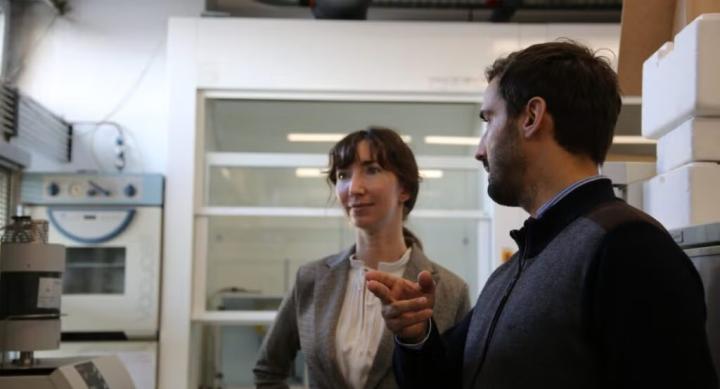 Two people talk to each other in a laboratory.