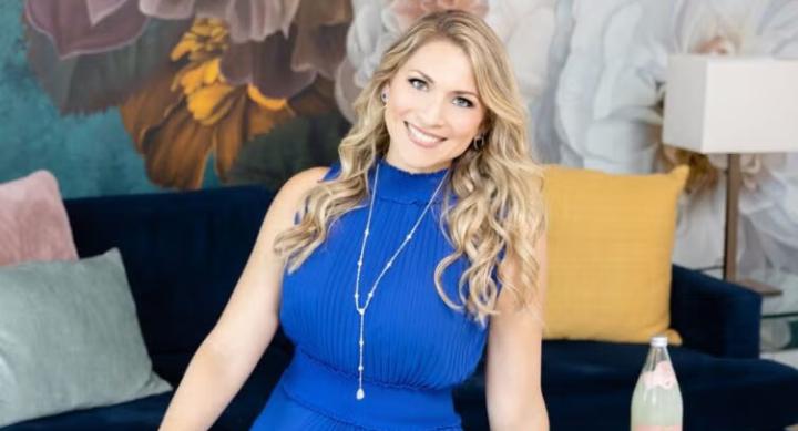 April Willis poses in front of a wall painted with flowers.