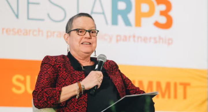 Susan Dawson sits holding a microphone as she speaks at the LONESTARP3 Summit.